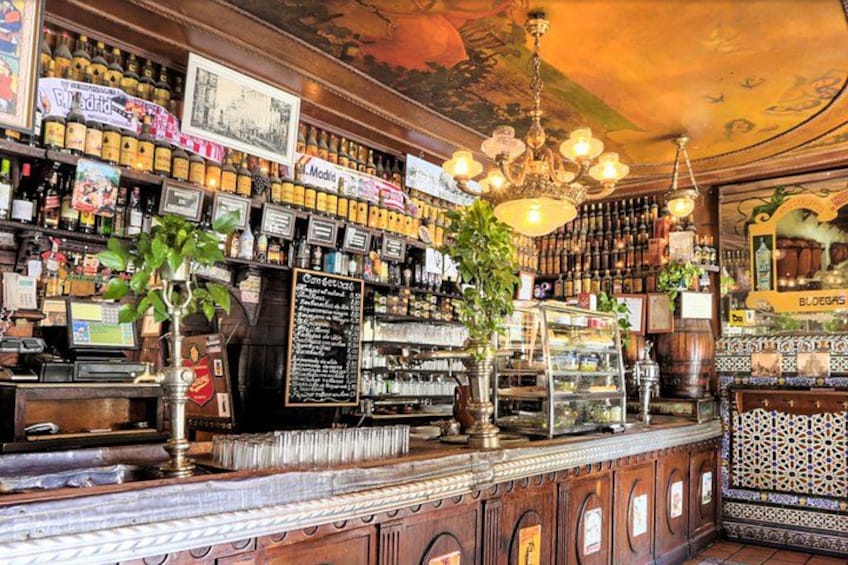 A bar with shelves of bottles, a cash register, and a chalkboard menu. 4