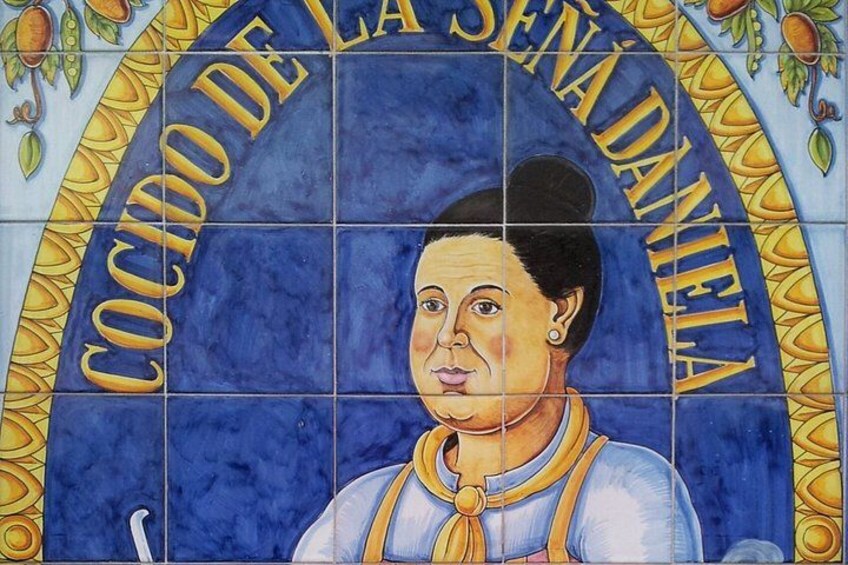 A tiled mural with a person wearing a blue and yellow outfit, surrounded by text and decorative elements. 3