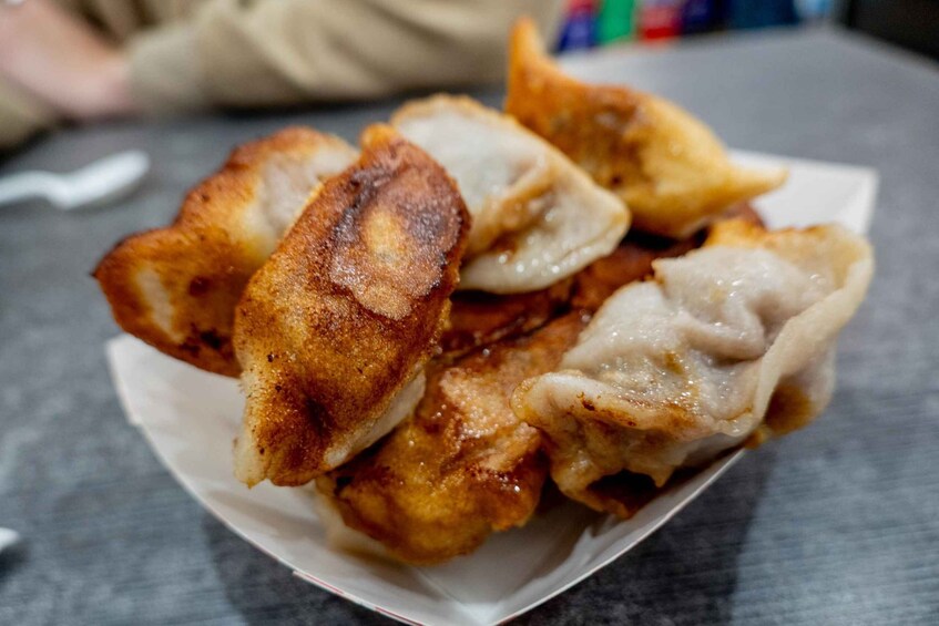 A plate of fried dumplings with a golden-brown crust. 3