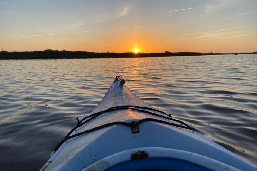 A kayak on calm water with a sunset in the background. 5