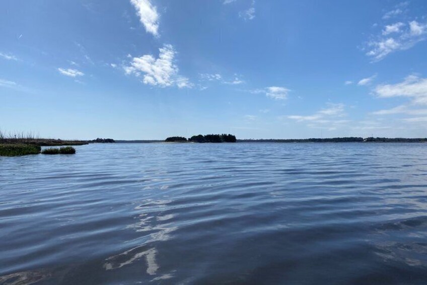 A calm body of water with a clear sky and distant landforms. 3