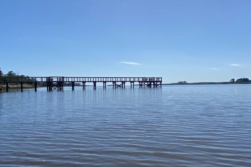 A wooden pier extending into calm water with a clear sky above. 5