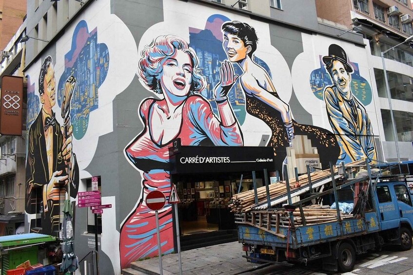 A mural on a building with a store named 'CARRÉD'ARTISTES' and a blue truck parked in front. 3