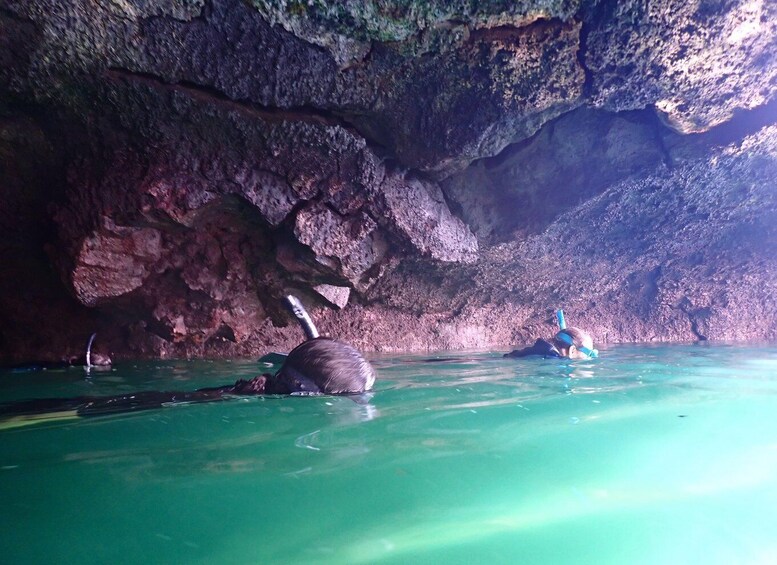A cave with clear water and a person snorkeling. 4