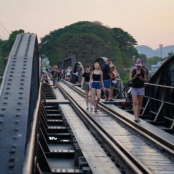 A pedestrian bridge with people walking, surrounded by greenery and hills. 5