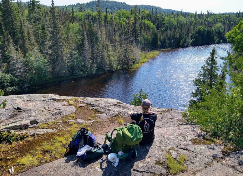 A person sitting on a rock overlooking a river with dense forest in the background. 5