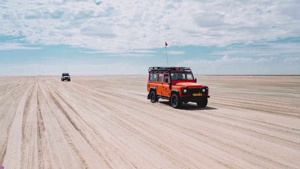 Two off-road vehicles on a vast sandy plain with a clear sky. 4