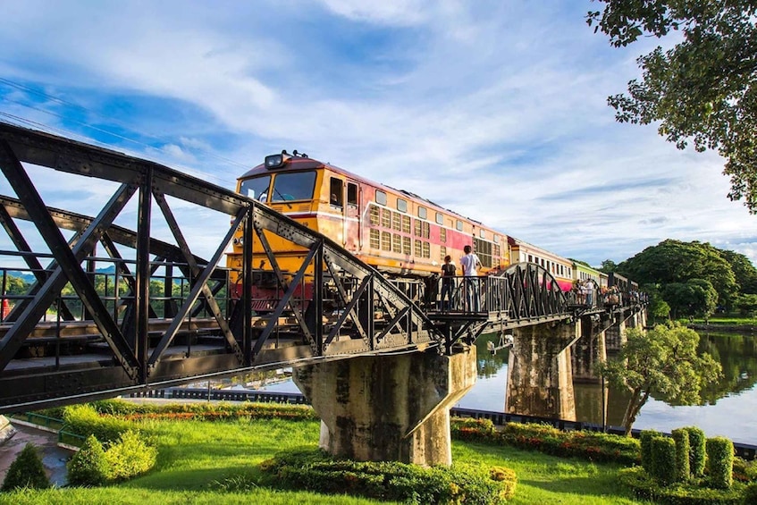 A train crossing a bridge over a body of water, surrounded by greenery. 1