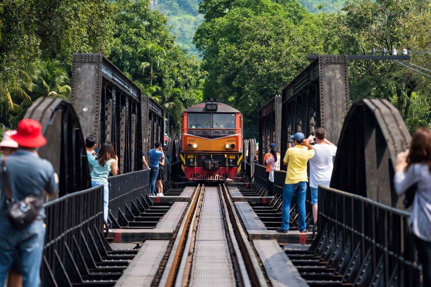 A train on a bridge surrounded by lush greenery. 2