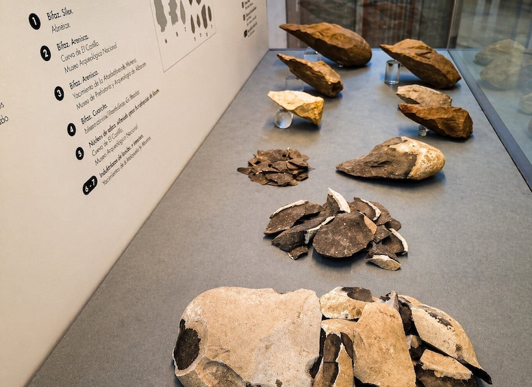 A museum display with various stone artifacts and a list of exhibits. 4