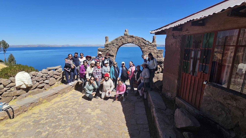 A group of people at a stone archway overlooking a body of water. 4