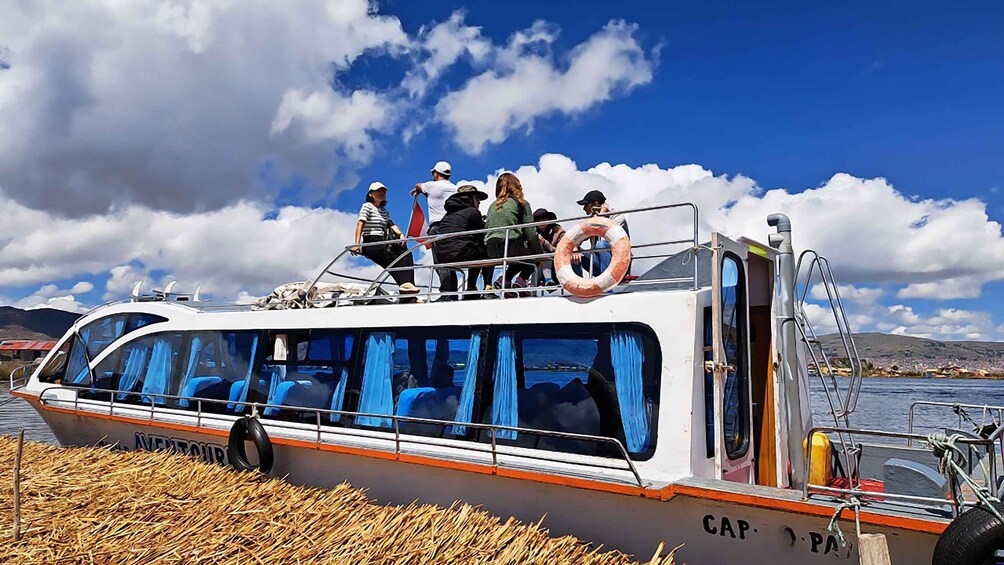 A boat with passengers on deck, a life ring, and a mountainous landscape in the background. 5