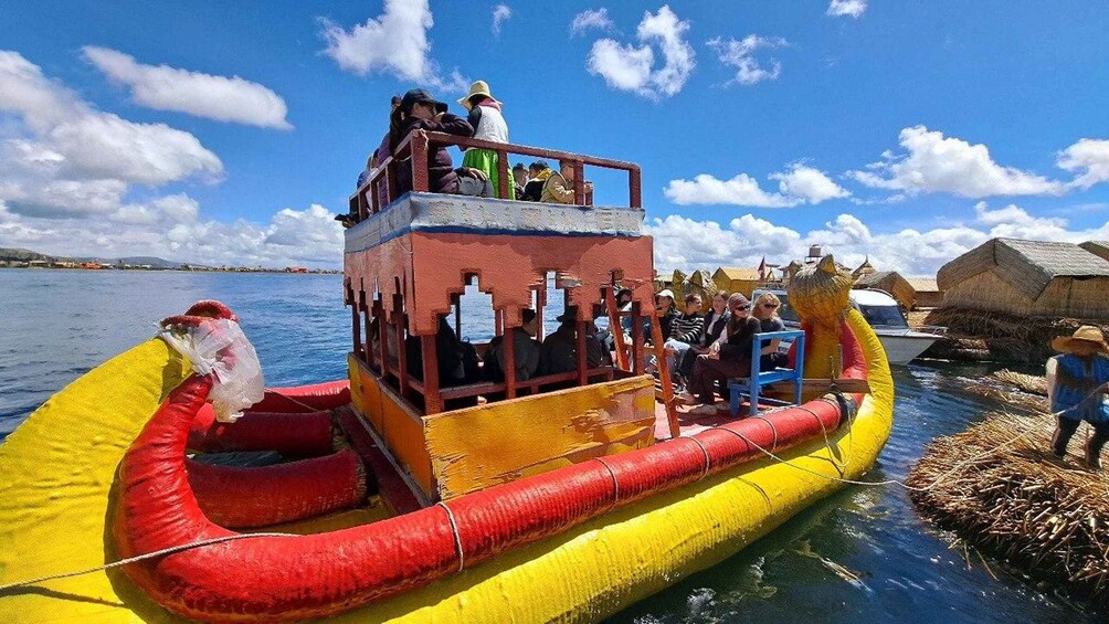 A colorful boat with passengers, a clear sky, and a calm body of water. 1