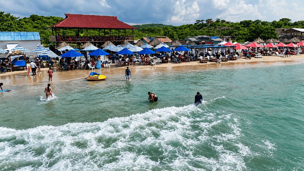 A beach with people swimming and a lifeguard on a yellow raft. 1