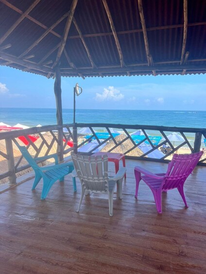 A wooden deck with colorful chairs overlooking a beach. 3