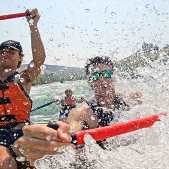A person in a life jacket holding a red paddle, splashing water. 2