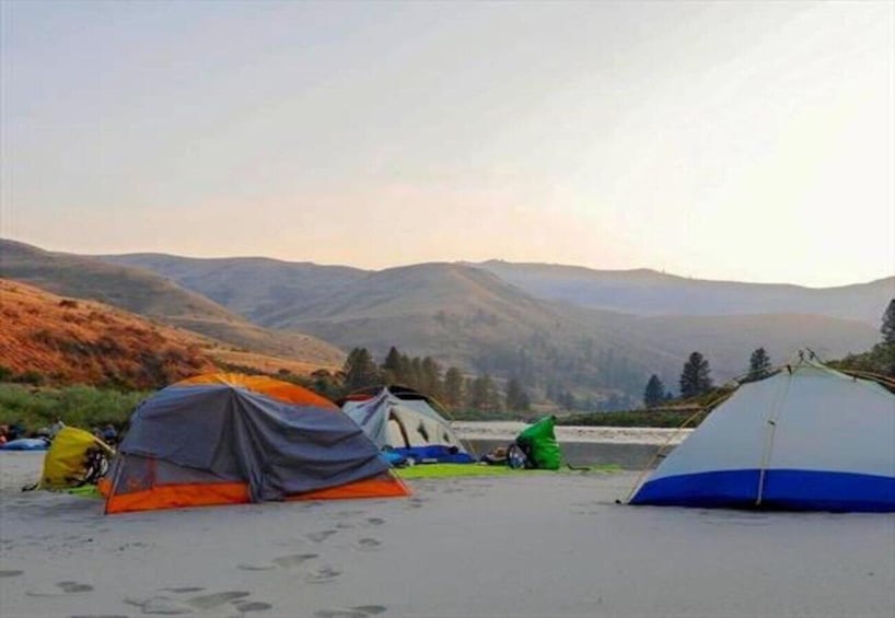 A campsite with tents on a beach, surrounded by mountains. 1