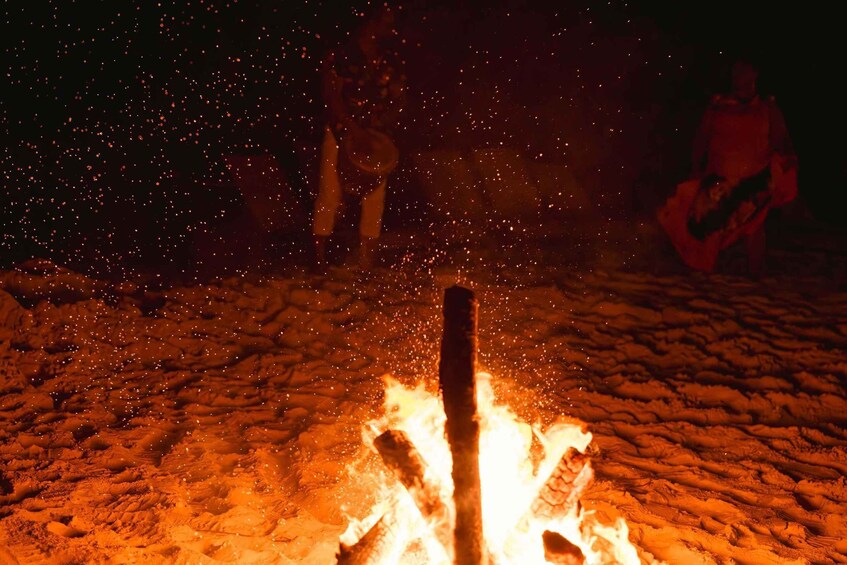 A campfire with sparks flying, surrounded by a sandy landscape. 2