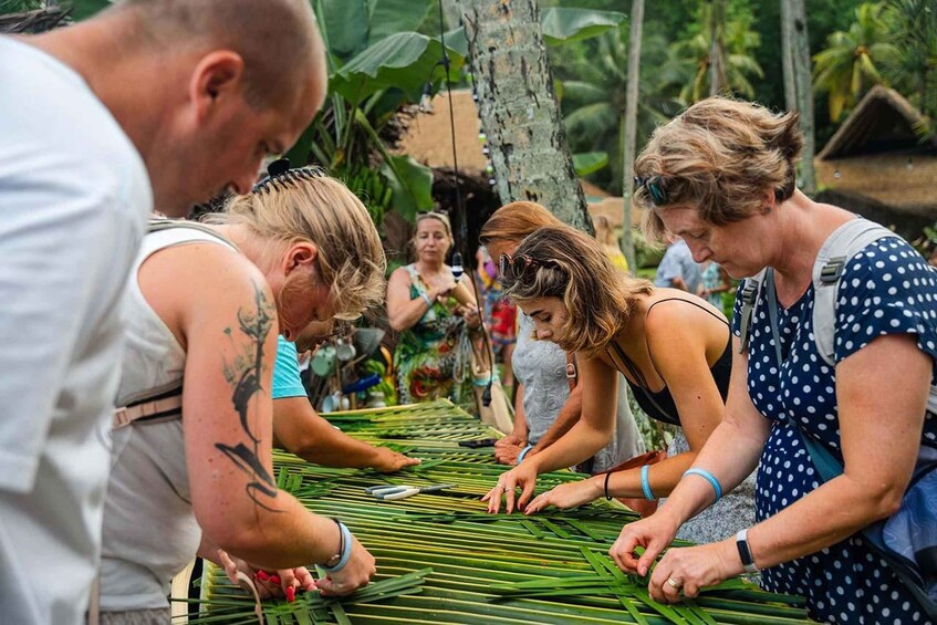 People engaged in a craft activity outdoors, surrounded by tropical vegetation. 3