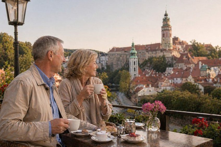Deux personnes sont assises à une table, devant des tasses, et contemplent une ville historique dont le clocher est particulièrement imposant. 1