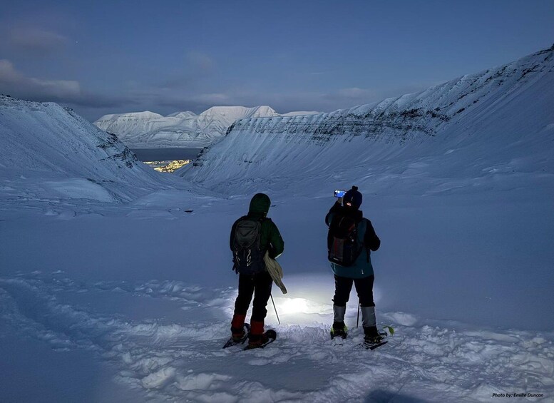 Two people skiing on a snow-covered slope with a valley in the background. 3