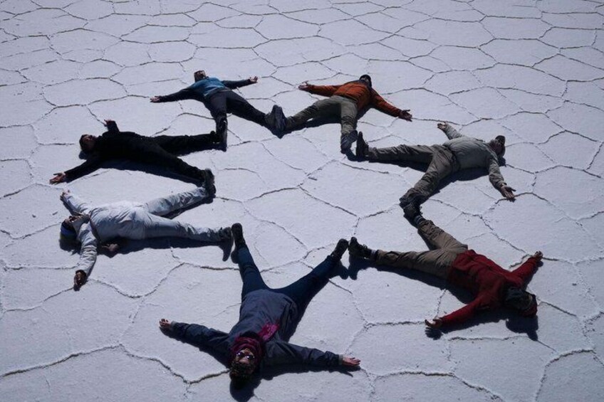 People lying on a cracked ground in a circle. 2