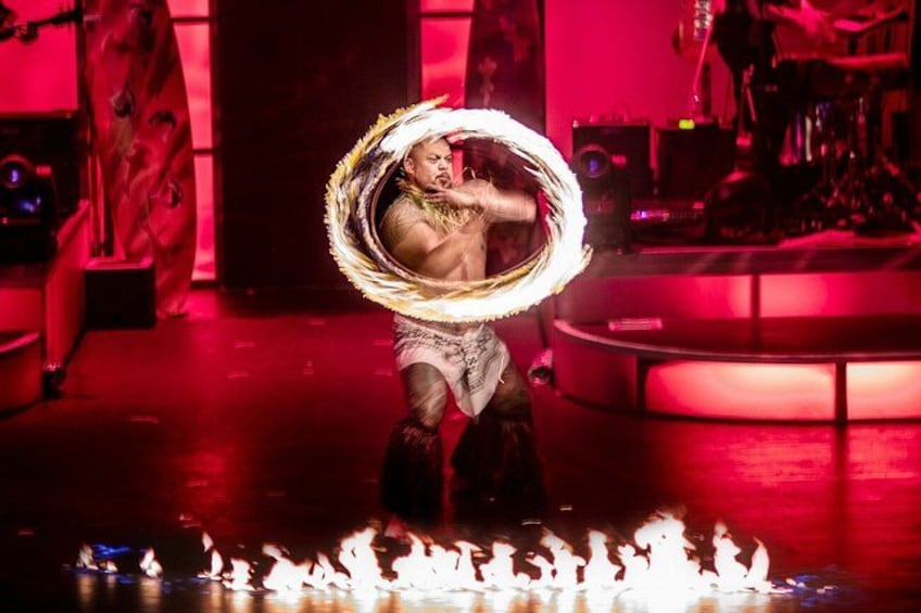 A performer with a flaming hoop, surrounded by fire on stage. 2