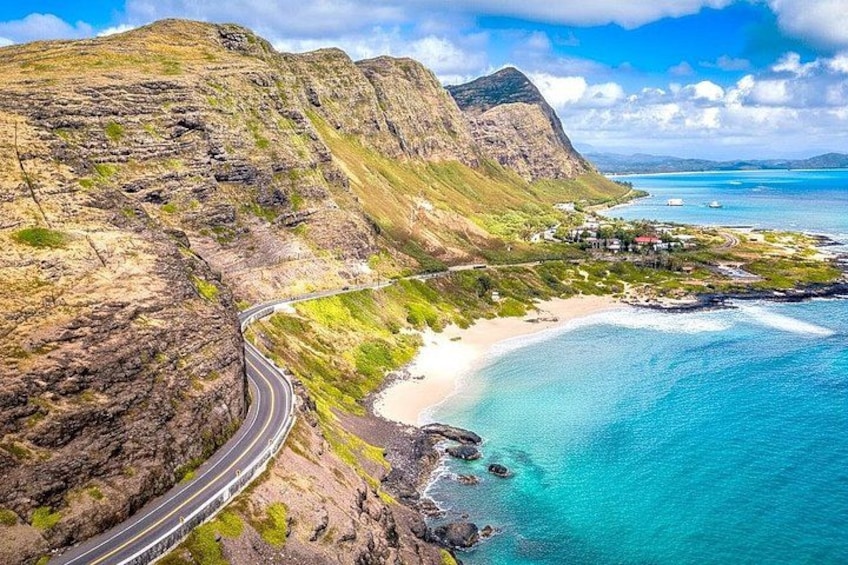 A coastal road winding through a mountainous landscape with a beach and clear blue waters. 3