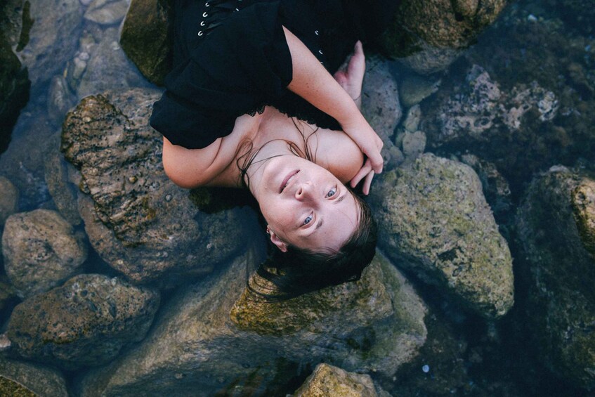 A person lying on rocks in a body of water. 2
