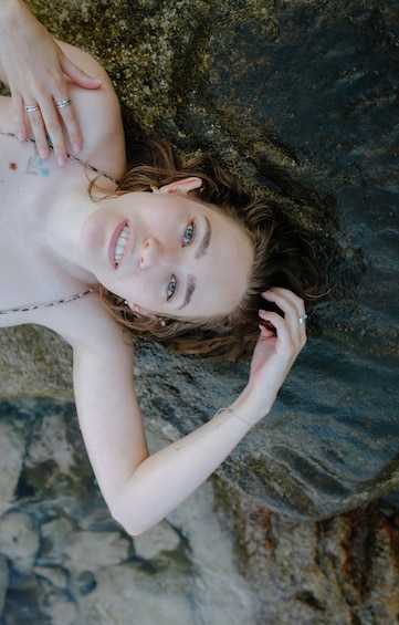 A person lying on a rocky surface with moss. 4