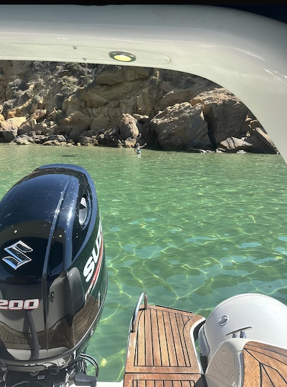 A boat with a Suzuki outboard motor, clear water, and rocky shoreline. 2