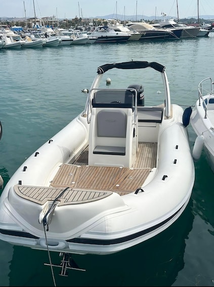 A white motorboat docked at a marina with other boats in the background. 1