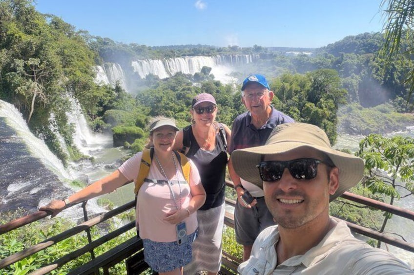 Un grupo de personas de pie sobre un puente, con una cascada al fondo. 1
