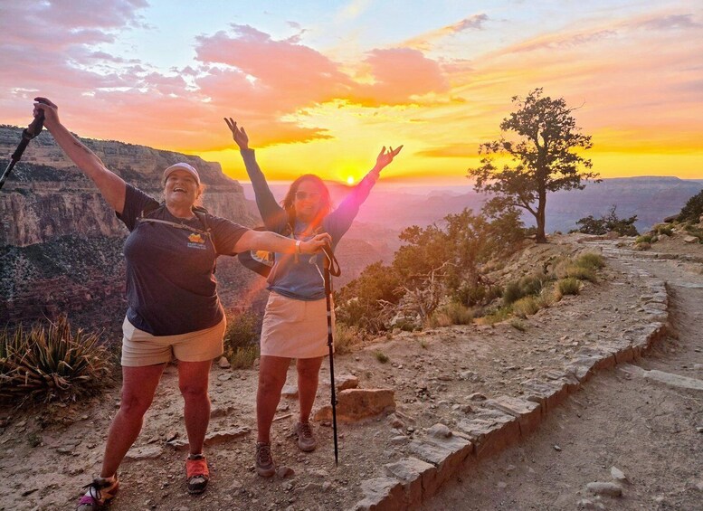 Two people hiking on a trail with a sunset in the background. 1