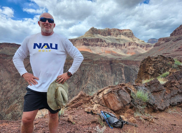 A person standing in a canyon with a backpack and hiking poles. 3