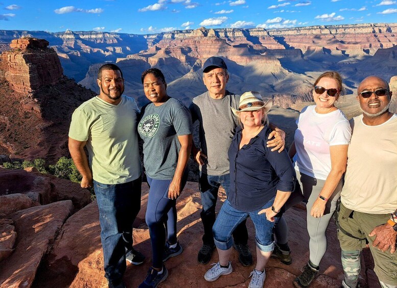 A group of people standing on a rocky outcrop with a canyon in the background. 5