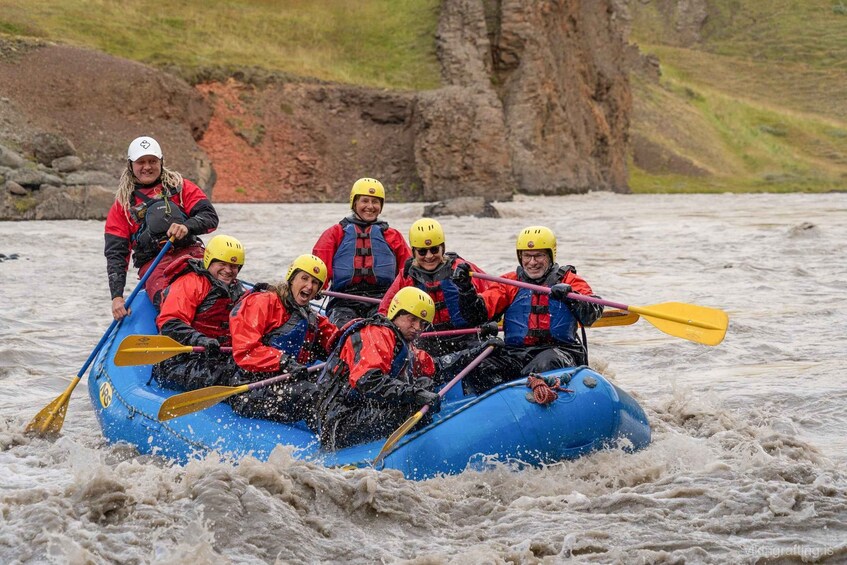 A group of people in a blue raft navigating through a river with rapids. 5