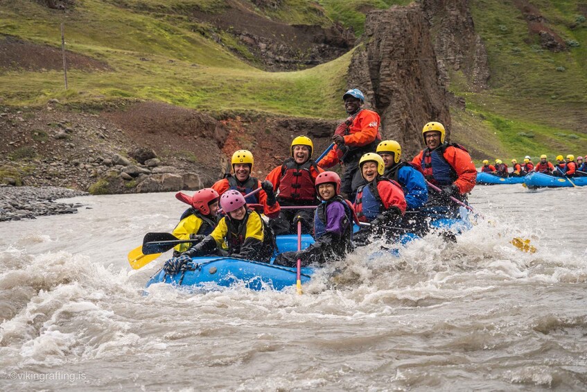 A group of people in a blue raft navigating a river with rapids. 2