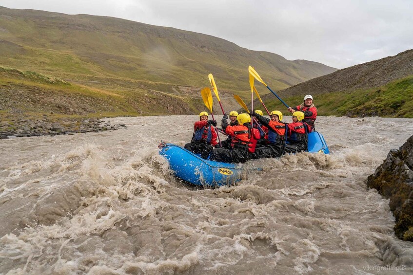A group of people in a blue inflatable raft navigating a turbulent river. 3