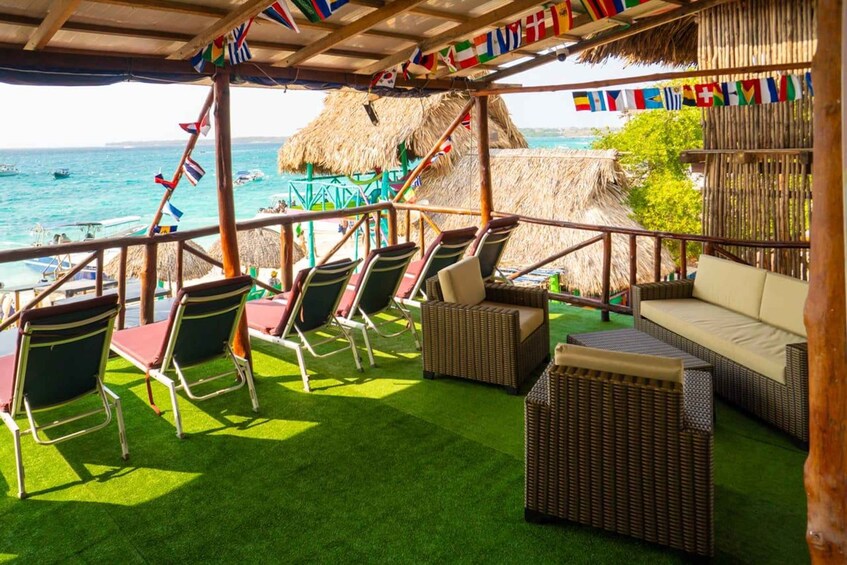 A beachside lounge with wicker furniture, a thatched roof, and a view of the ocean. 2
