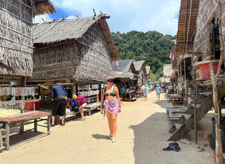 A market street with thatched-roof buildings, a woman walking, and various stalls. 4