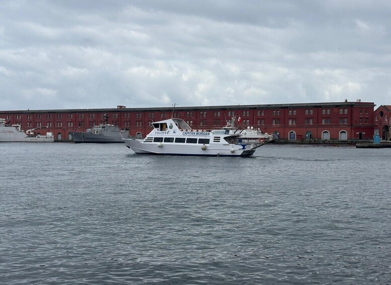 A white boat named 'CAPITAN MORGAN' on calm water with a red building in the background. 4