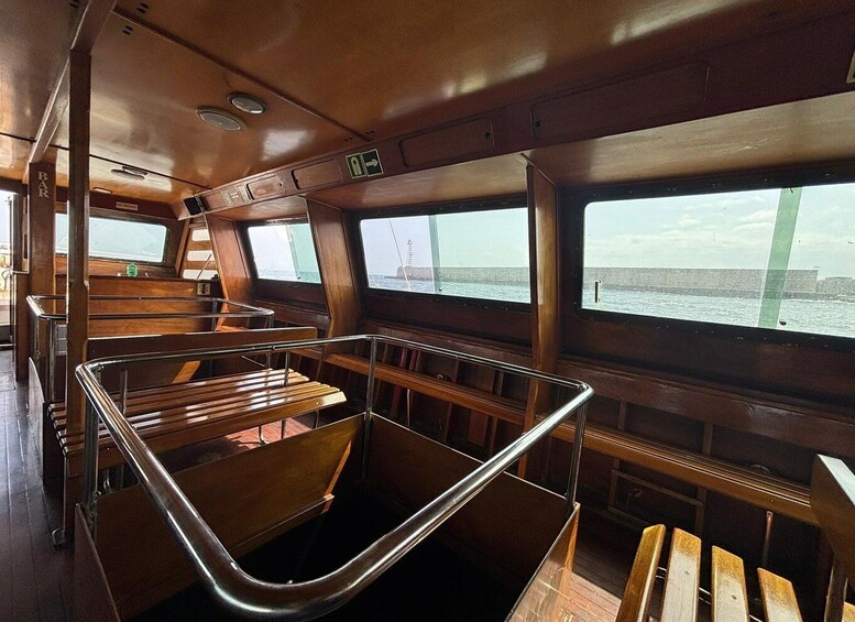 A ship's interior with wooden seating and windows overlooking the sea. 3