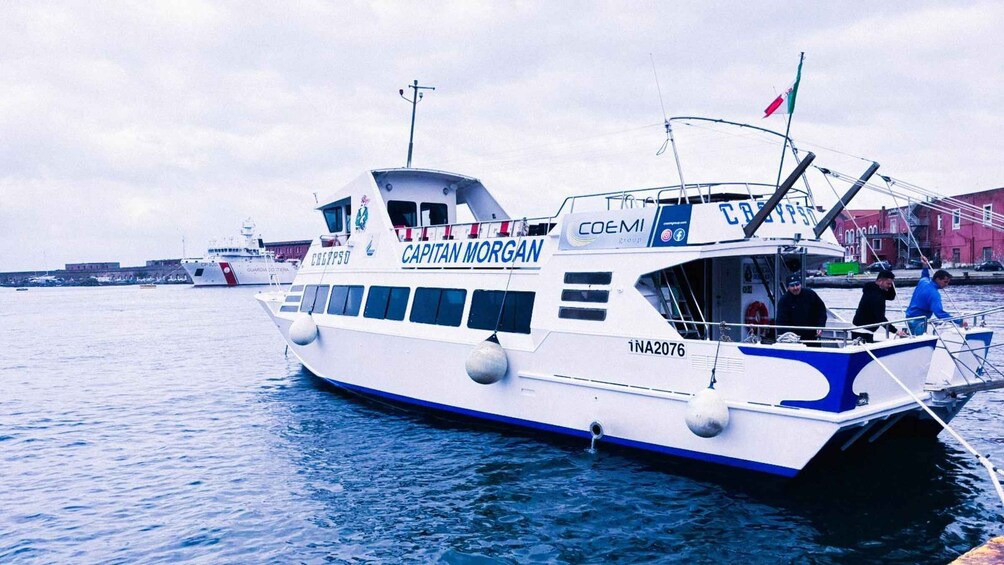 A white and blue boat named 'CAPITAN MORGAN' with the registration number 'INA2076' docked at a port. 1