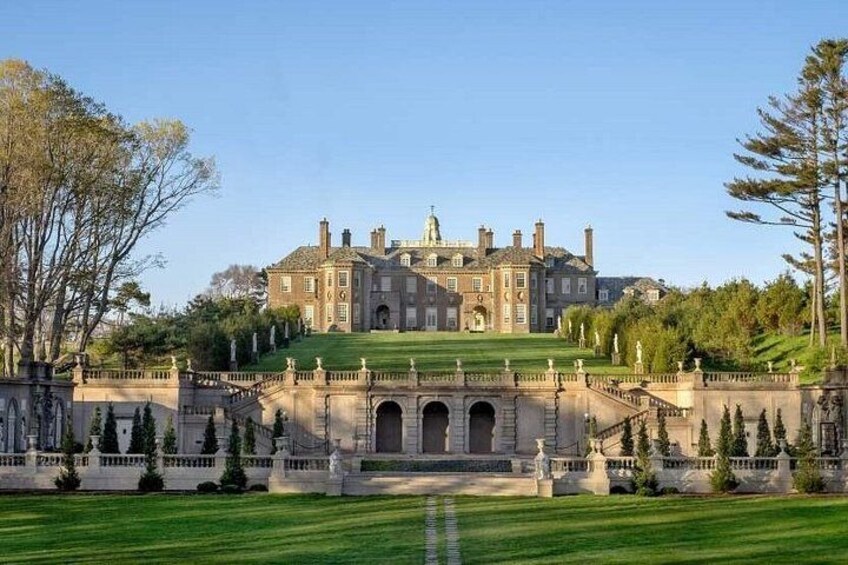 A large stately mansion with a symmetrical facade, a central entrance, and a well-manicured lawn. 2
