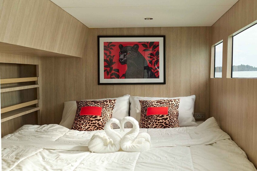 A hotel room with a bed, two leopard print pillows, a framed picture of a leopard, and a window. 5