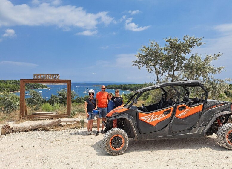 A group of people standing next to a Buggy Safari vehicle with a scenic coastal background. 4