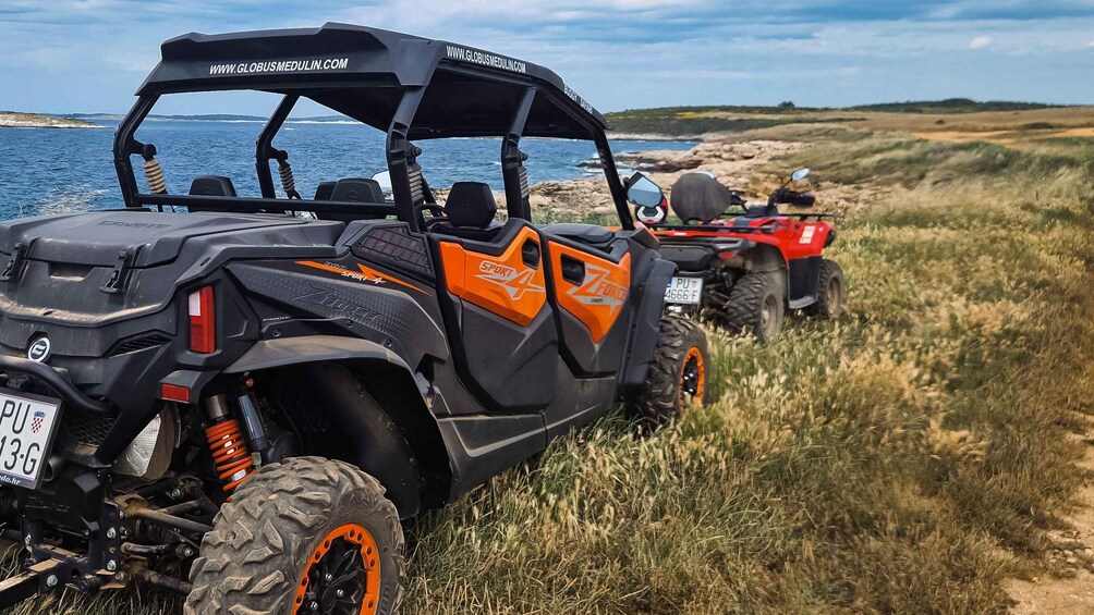 A black and orange off-road vehicle with a visible license plate PU 13-G, parked on a grassy path by the sea. 2