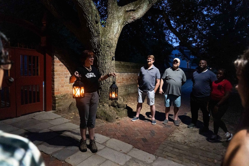 A group of people standing on a brick pathway at night, holding lanterns. 5