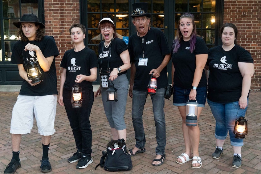 A group of people holding lanterns and wearing black t-shirts with 'US GHOST Adventures' printed on them. 1